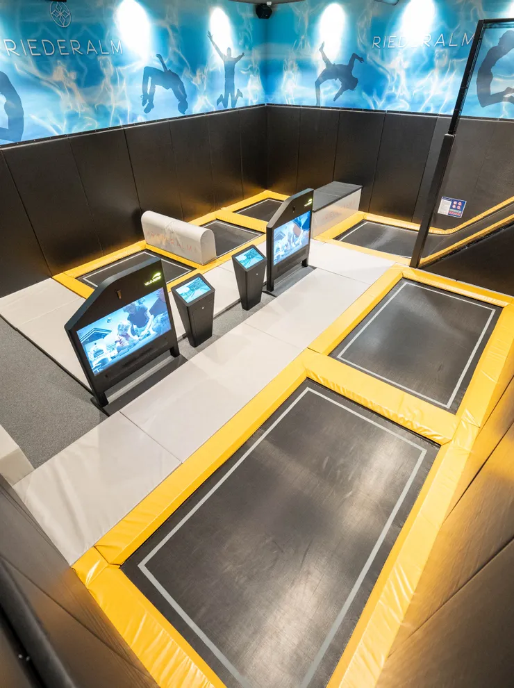 Indoor trampoline park with touchscreen displays and padded walls at Riederalm